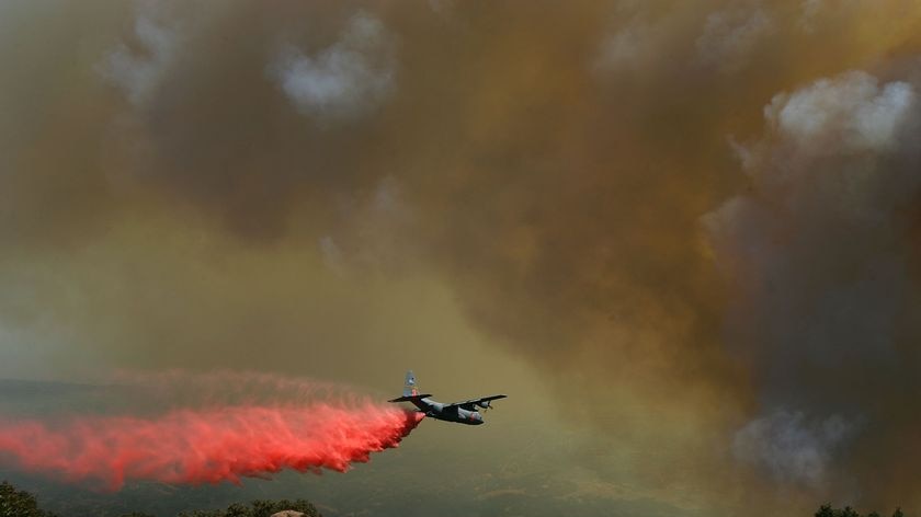 A firefighting airtanker drops Phos-Check fire retardant in California