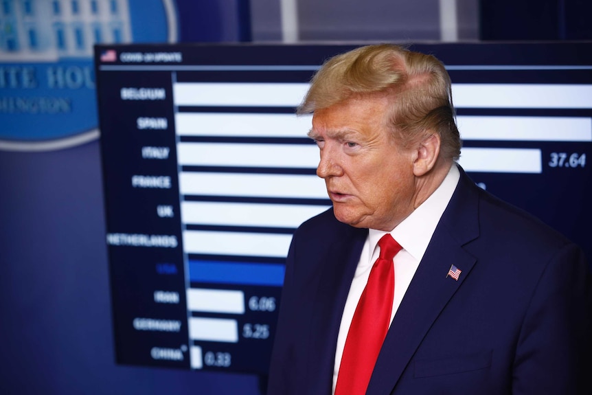 US President Donald Trump, wearing a navy suit, looks on.