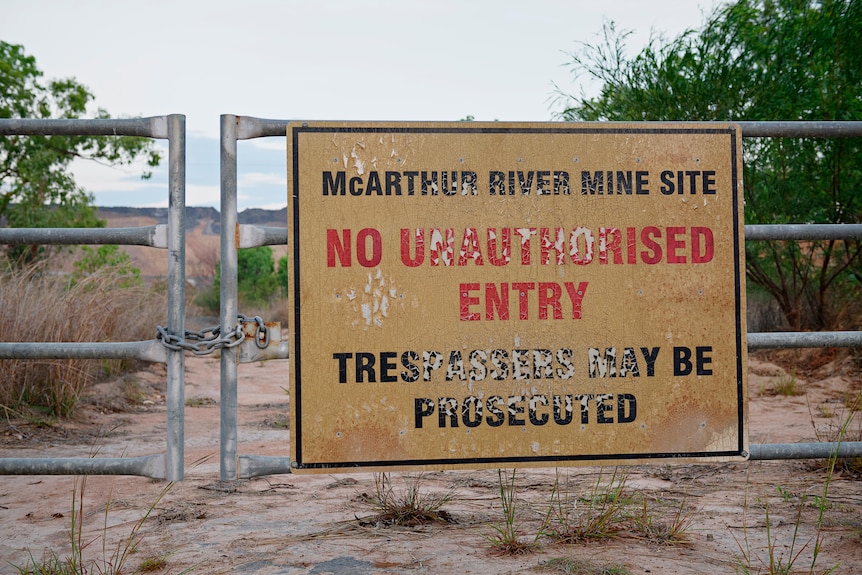 A locked gate with a large 'no unauthorised entry' sign affixed to it. 