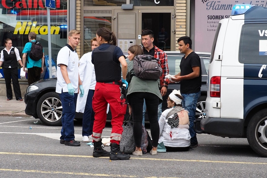 Victims sit i the street nearby a large square in Finland where a stabbing attack occurred.