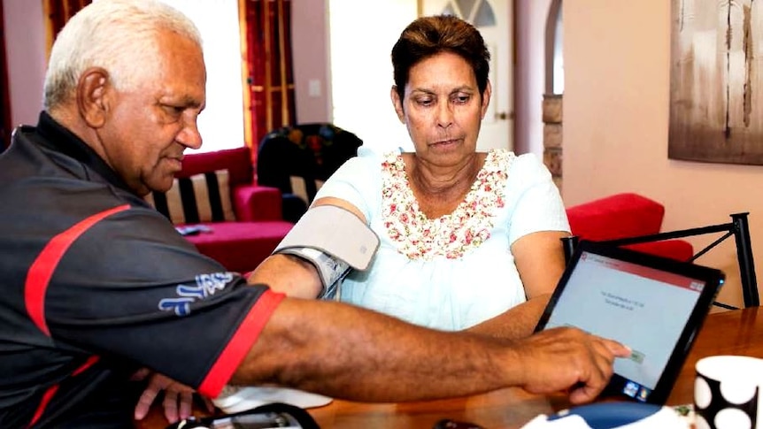 A patient has a blood pressure reader attached to her arm, with the results being sent to a tablet.
