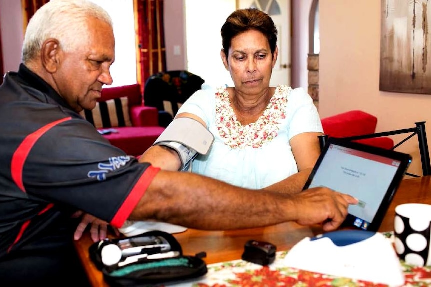 A patient has a blood pressure reader attached to her arm, with the results being sent to a tablet.