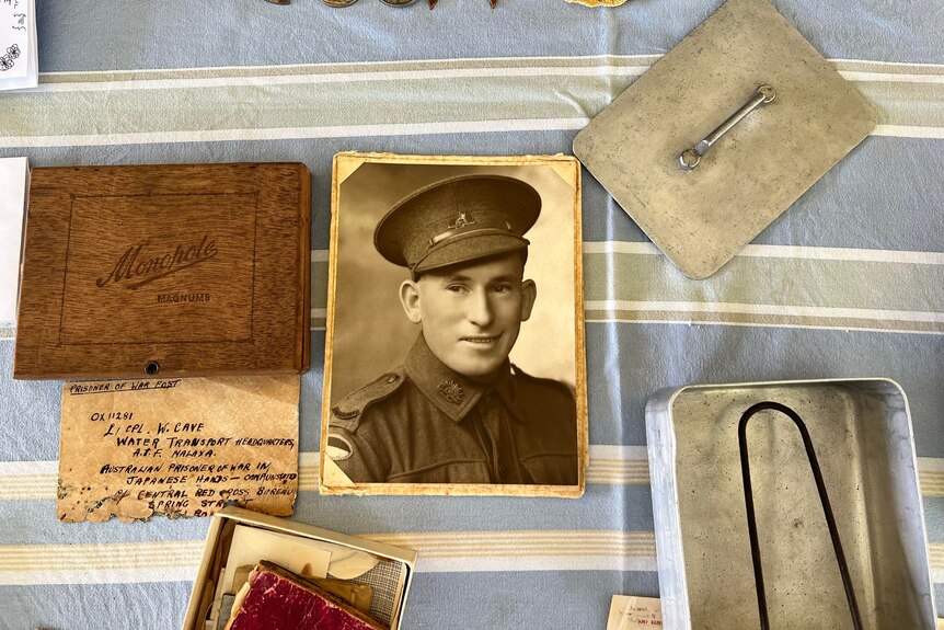 An old photo, notebook and meal tin from the war laid out on a table.