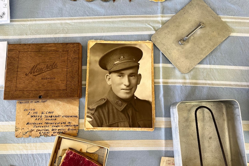 An old photo, notebook and meal tin from the war laid out on a table.