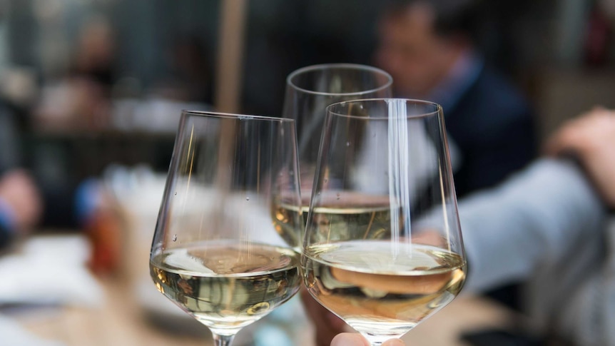 People clinking three glasses of white wine