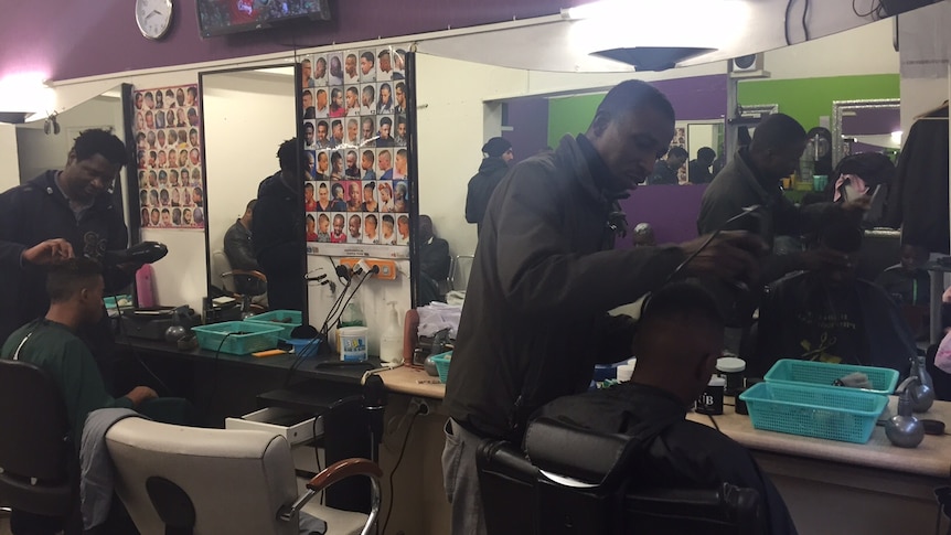 Barbers' cutting hair in a shop in Paris.
