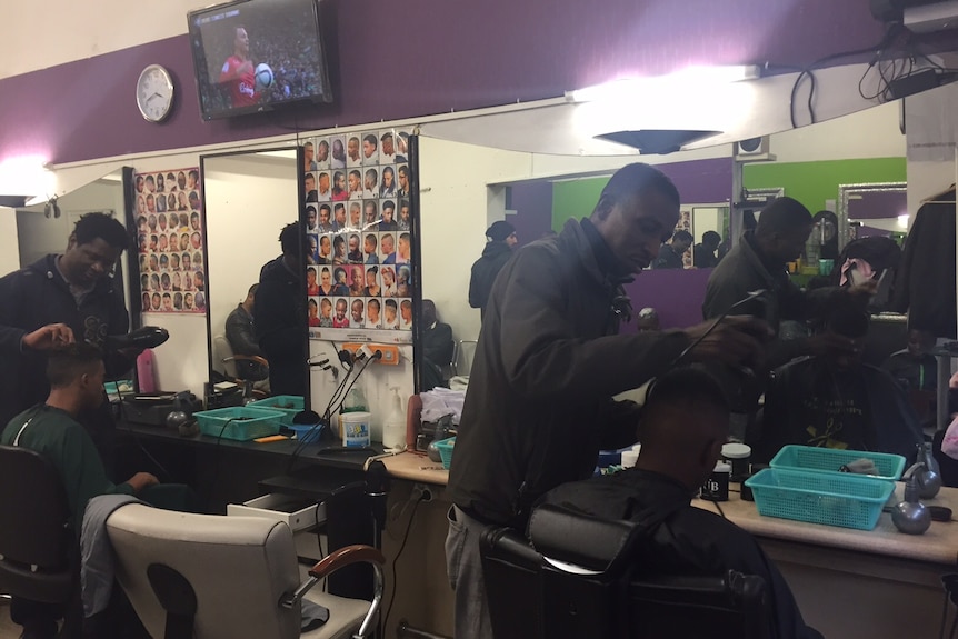 Barbers' cutting hair in a shop in Paris.