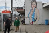 Pedestrians walk past a mural of Democrat US presidential nominee Hillary Clinton clad in a swimsuit