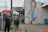 Pedestrians walk past a mural of Democrat US presidential nominee Hillary Clinton clad in a swimsuit