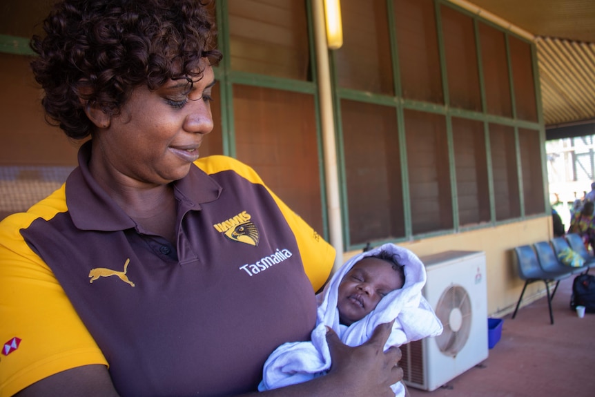 A lady holding a baby.