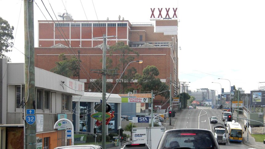 Vehicles move down Milton Road past the XXXX Brewery heading towards the city.