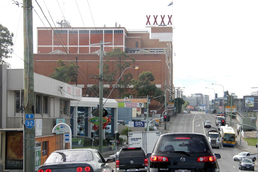Vehicles move down Milton Road past the XXXX Brewery heading towards the city.