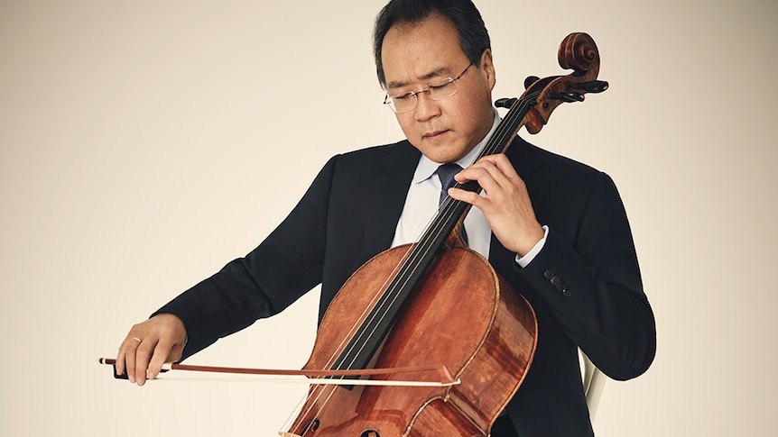 Cellist Yo-Yo Ma plays cello in a black suit. His eyes are closed and his head is tilted toward his cello.