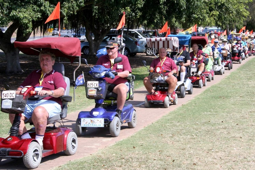 People ride scooters with flags in a convoy