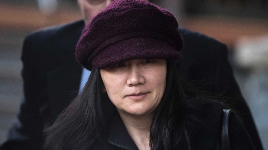 Huawei chief financial officer Meng Wanzhou wears a black coat and purple hat as she walks outside