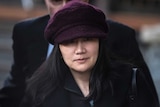 Huawei chief financial officer Meng Wanzhou wears a black coat and purple hat as she walks outside