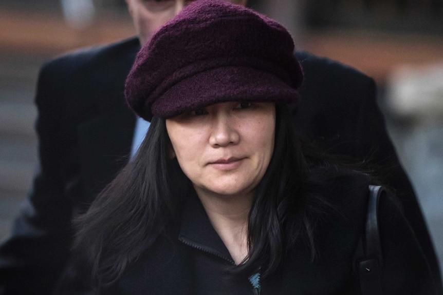 Huawei chief financial officer Meng Wanzhou wears a black coat and purple hat as she walks outside