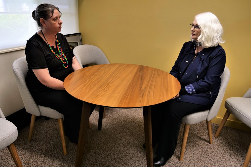 two women sit at an office table