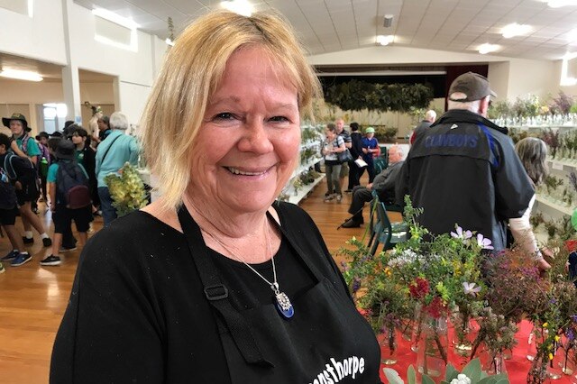 A smiling Sue Leighton standing next to a wildflower display table.