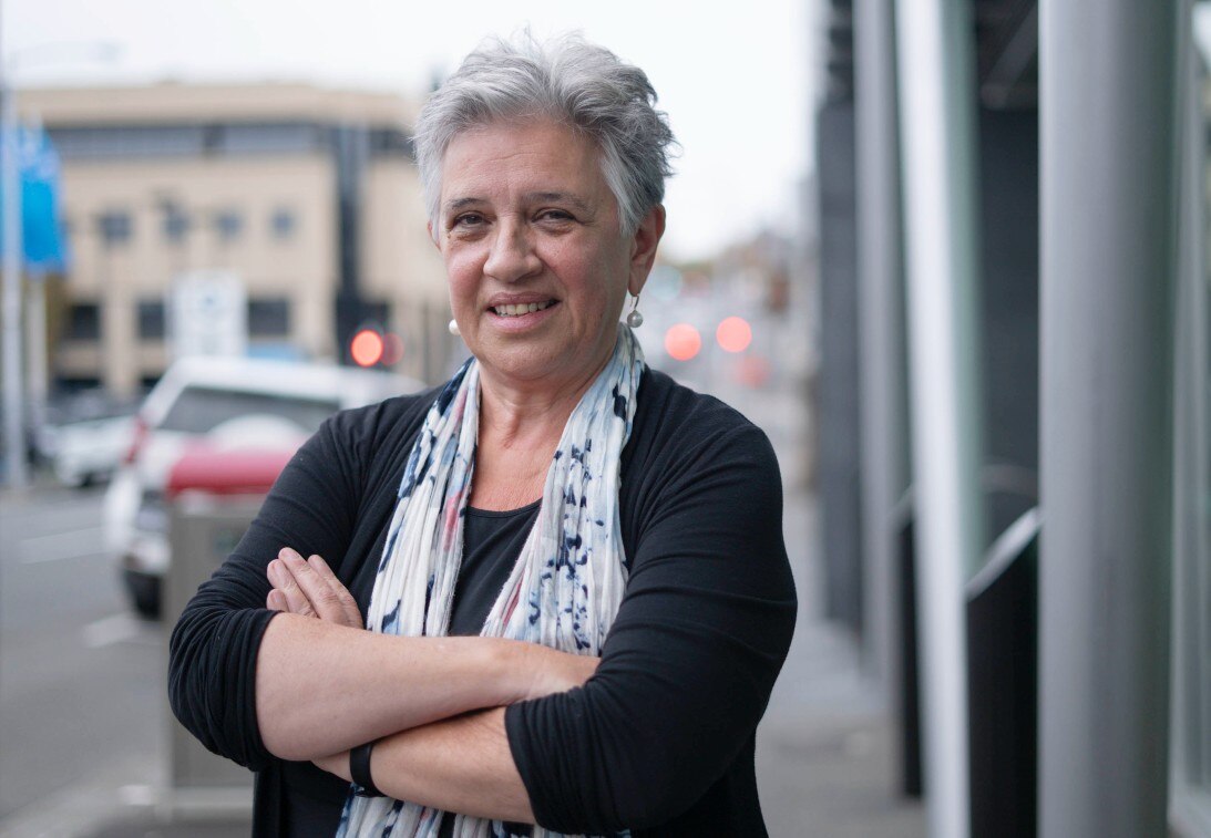 A woman with silver hair crosses her arms.