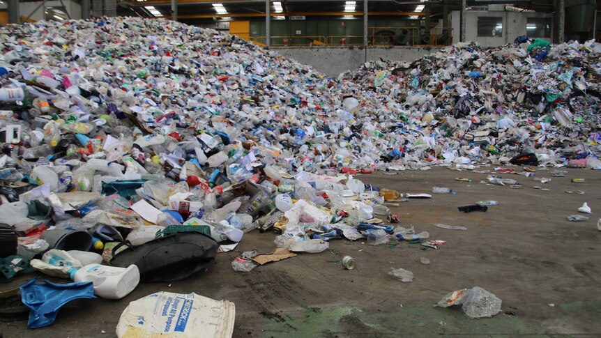 Large piles of waste such as plastic bottles and containers in a waste collection centre.