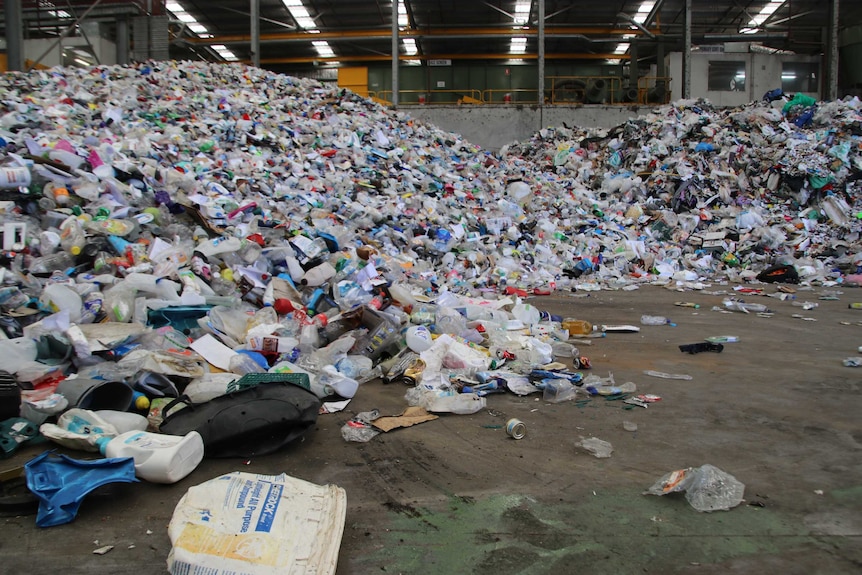 Large piles of waste such as plastic bottles and containers in a waste collection centre.