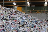 Large piles of waste such as plastic bottles and containers in a waste collection centre.