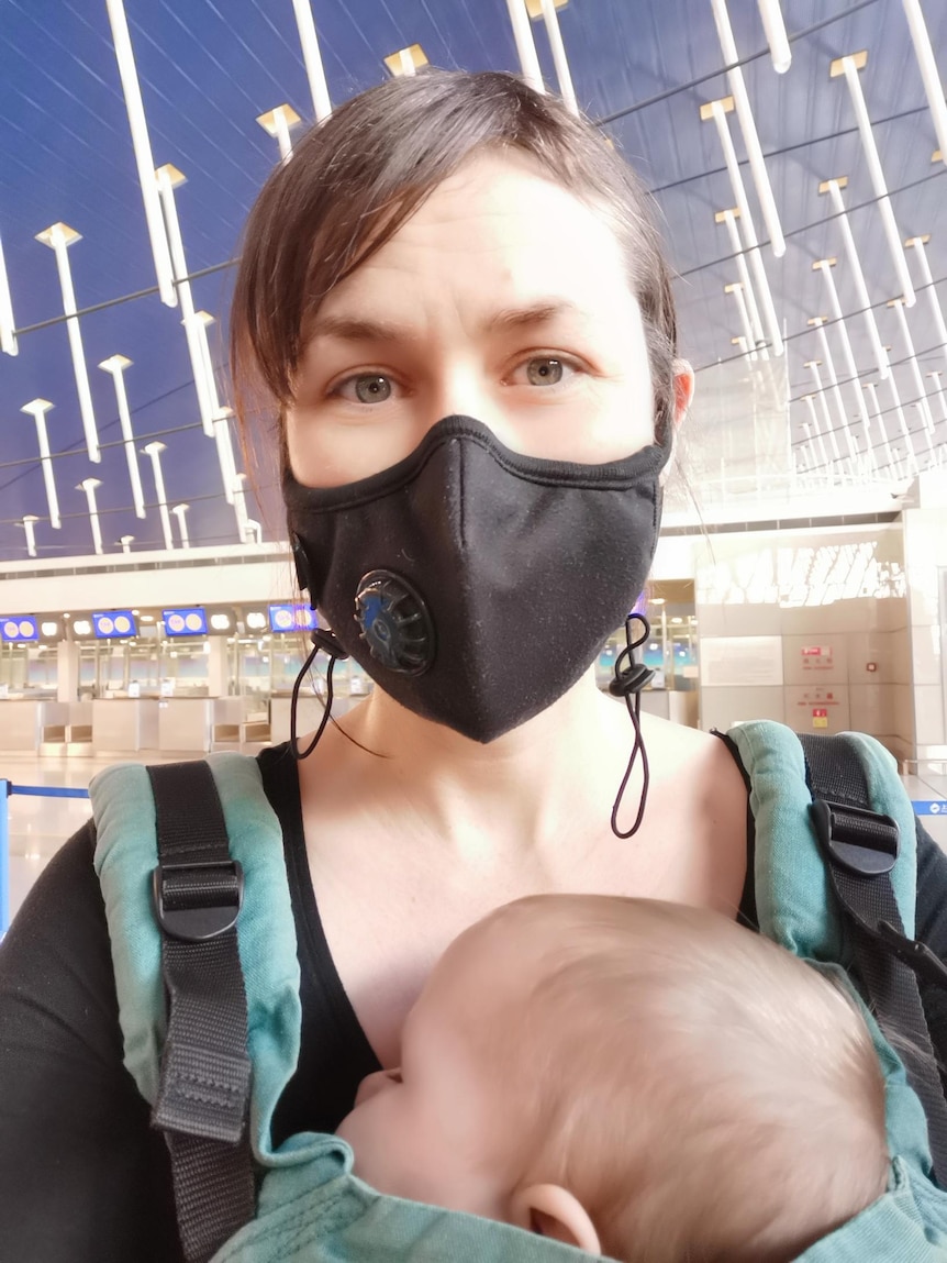 A portrait of Vivian wearing a black mask inside an airport.