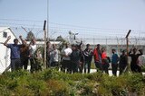 Migrants look through a fence from inside the Moria registration centre