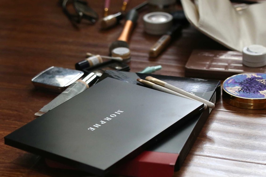 Several brushes and colours of makeup scattered on a table