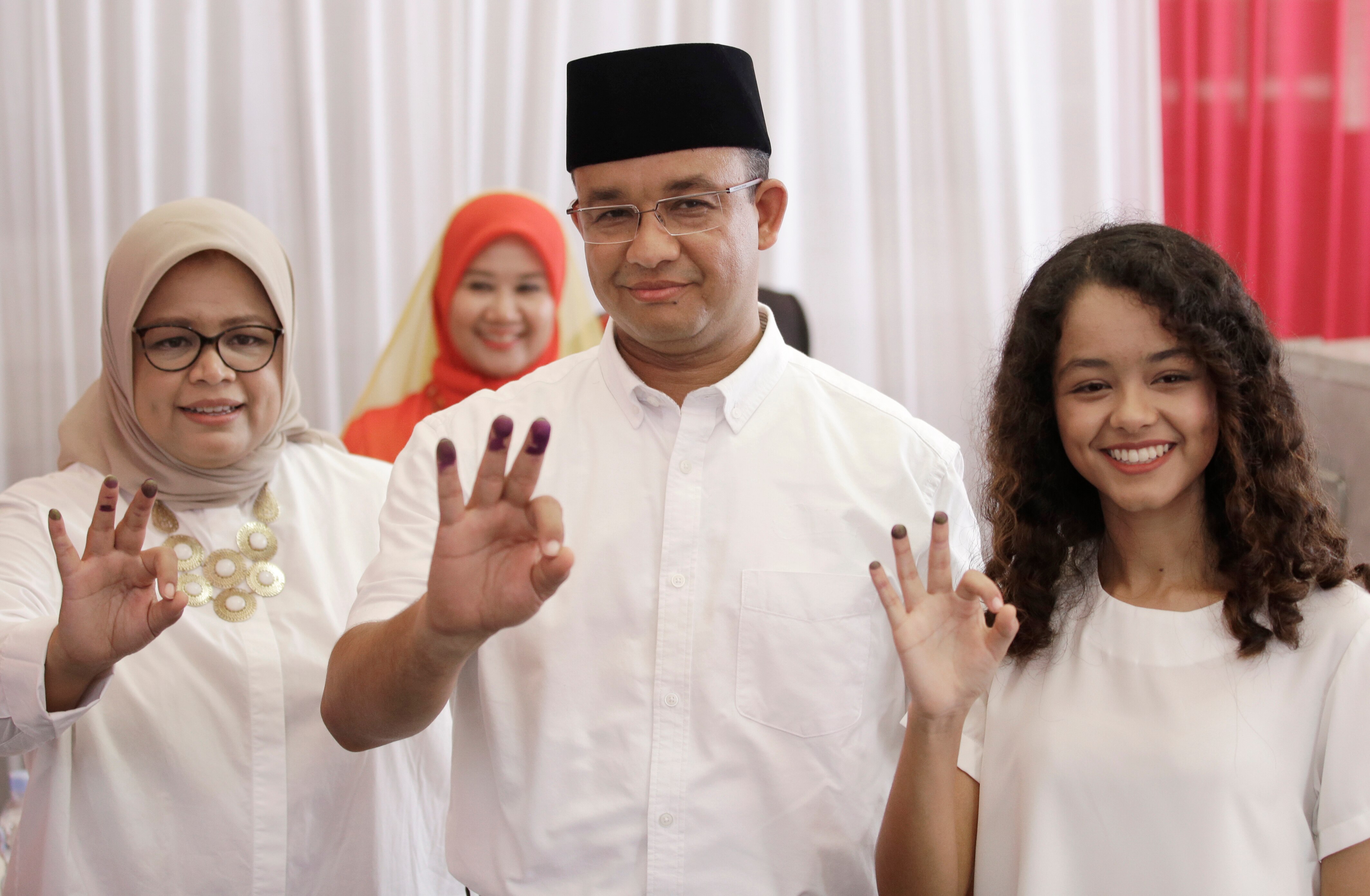 Anies Baswedan, centre, his wife Fery Farhati Ganis, left, and daughter Mutiara show their ink-dipped fingers
