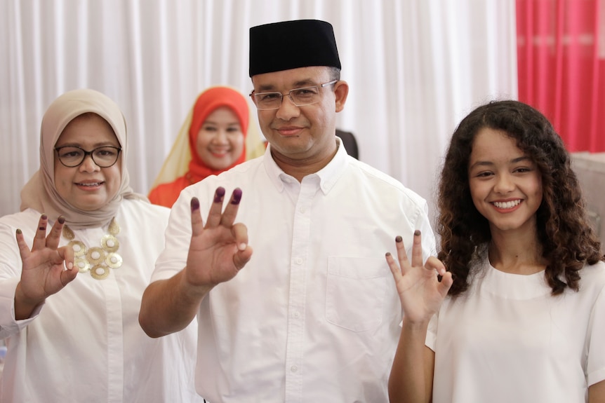 Anies Baswedan, centre, his wife Fery Farhati Ganis, left, and daughter Mutiara show their ink-dipped fingers