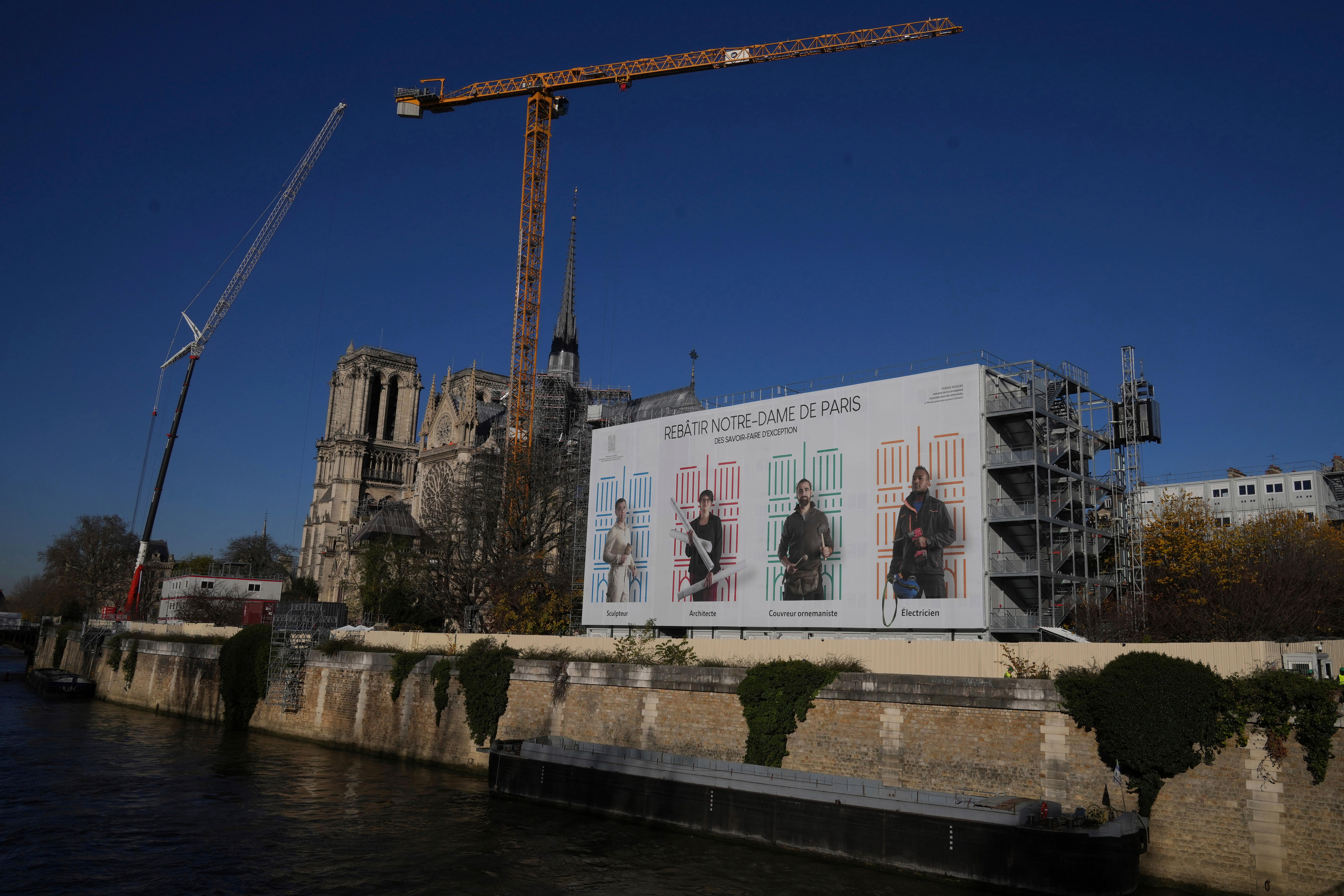 A white billboard showing four people outside the Notre Dame cathedral