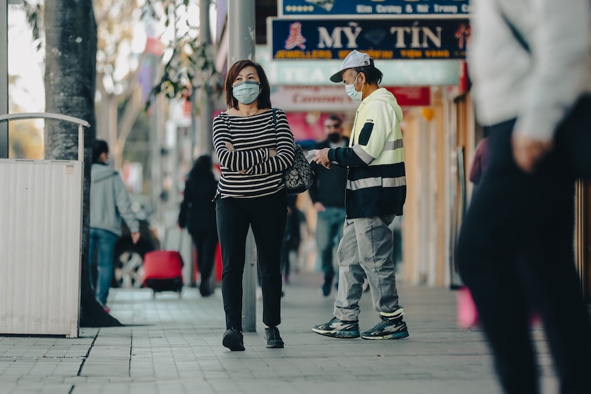 a woman wearing a mask and walking on a street