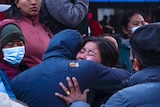 A woman crying in Nepal while embracing a person in coat. 