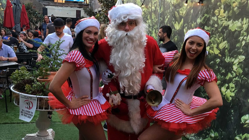 Rodney Meyer dressed up as Santa Claus with two elves