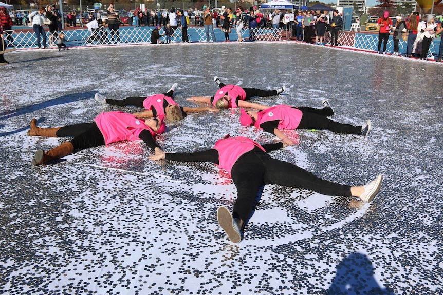 Four women lying in five cent coins making snow angels