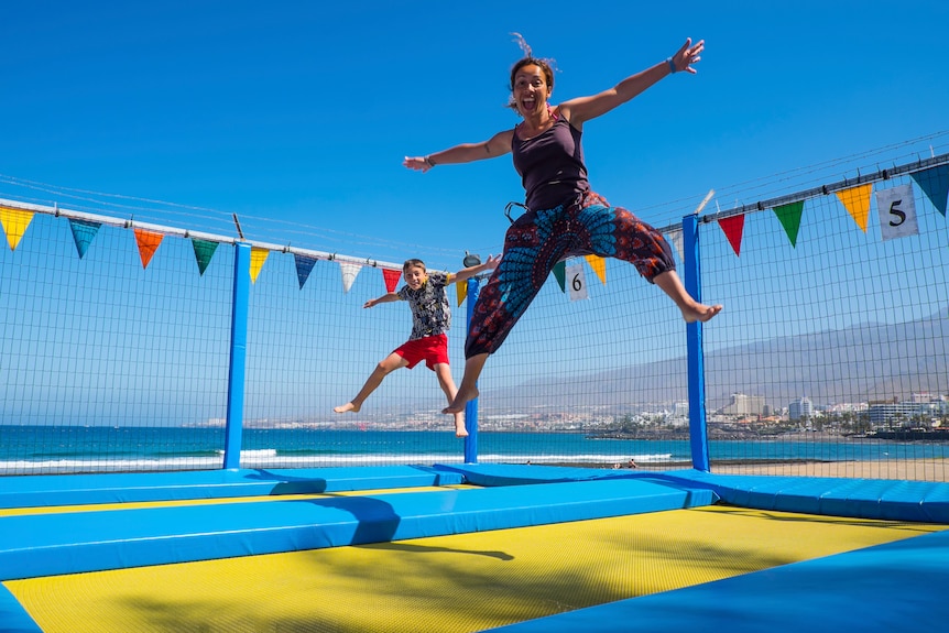 Mother and son bouncing on a trampoline.