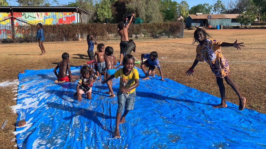 Young Indigenous children playing on a slip in slide in a park in a remote community