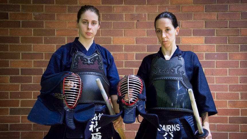 Two female kendoka look menacingly into the camera as they prepare to face off against one another.