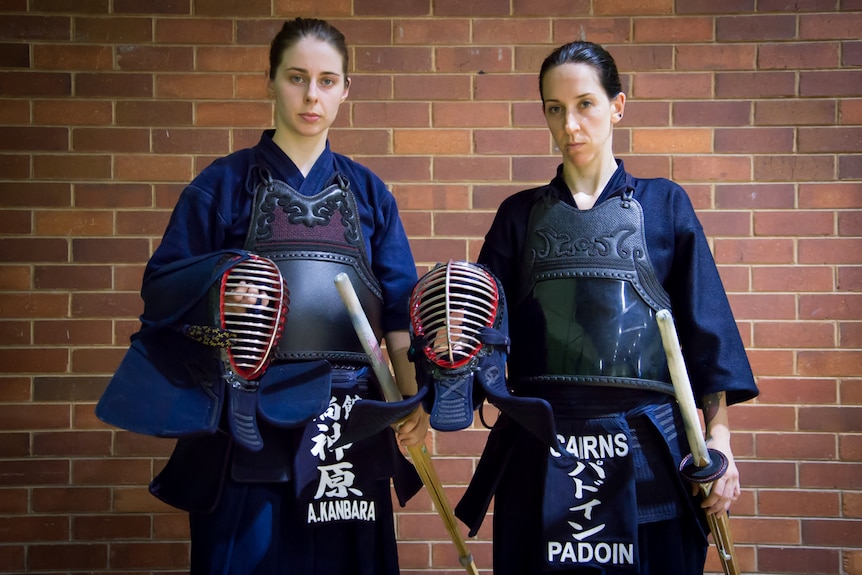 Two female kendoka look menacingly into the camera as they prepare to face off against one another.