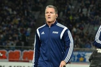 A soccer referee walks along the touchline.