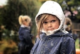 A small mud-splattered child stares at the camera.