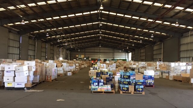 A large warehouse with pallets of stationary scattered throughout.