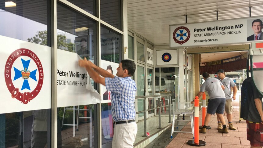 Man removes exterior signage from his office.