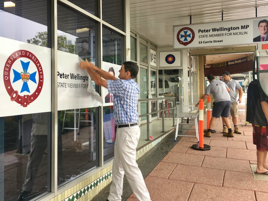 Man removes exterior signage from his office.