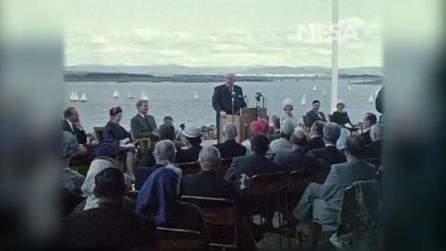 People sit at ceremony in front of Lake Burley Griffin