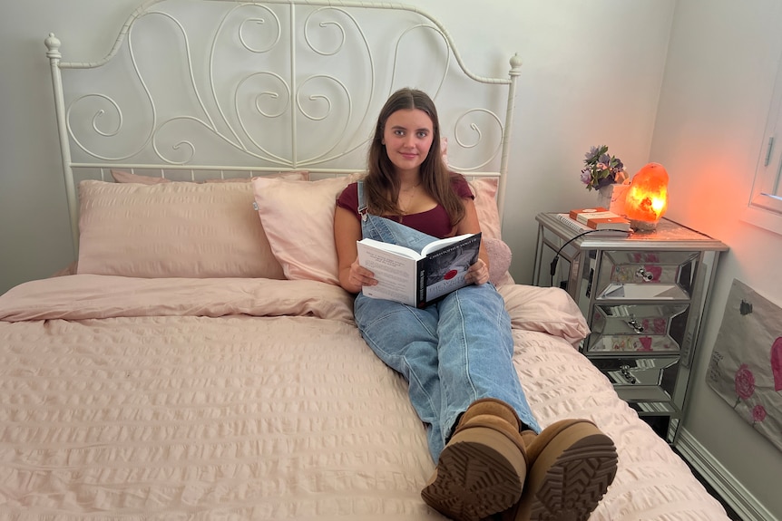 a girl sitting on her bed with a book