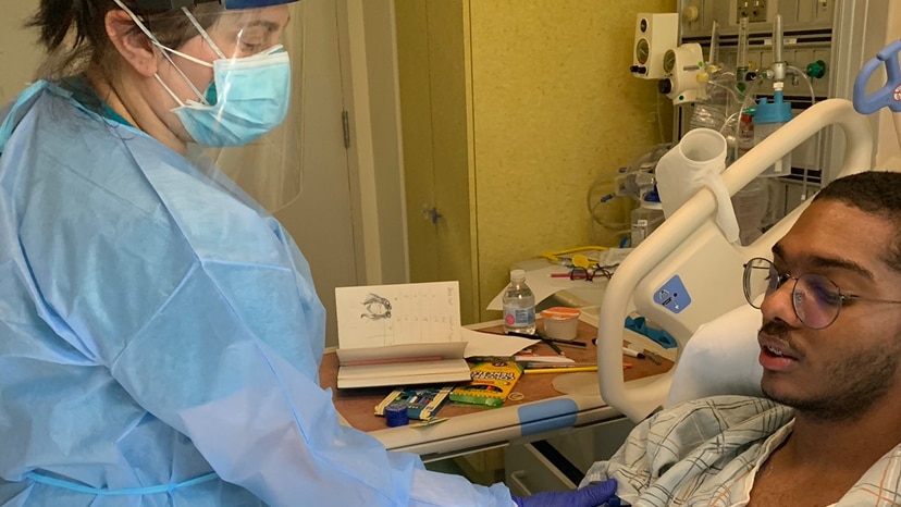 David Vargas lying in a hospital bed being treated by a nurse.