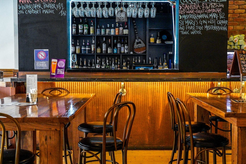 A bar with a wooden interior, chairs and tables.